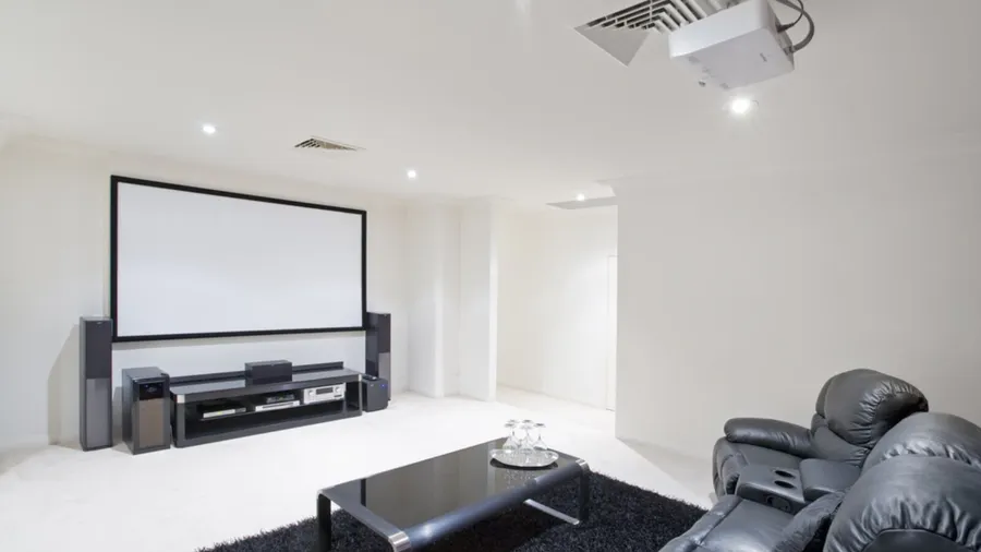 Home theater room with black leather recliner chairs, black rug and table.