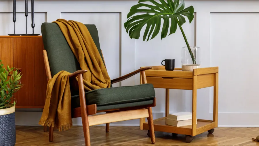 A stylish living room interior with retro armchair, wooden coffee table, and potted plant.