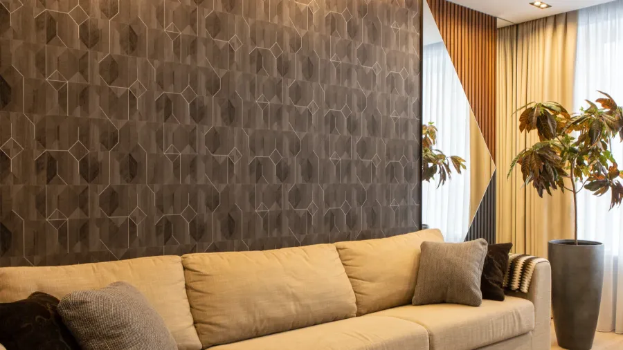 An earthy neutral living room interior with sofa with cushions, potted plant, and wallpaper.