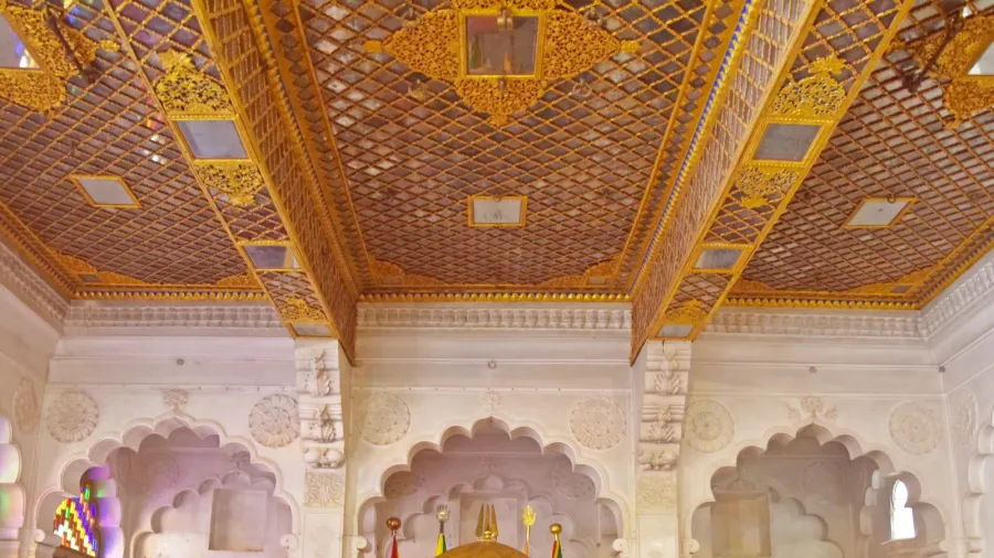 A grand Indian palace balcony with a richly decorated golden ceiling and detailed ceiling work.