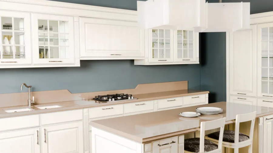 A traditional kitchen features white cabinetry, a beige countertop, and a modern pendant light with ample storage space.