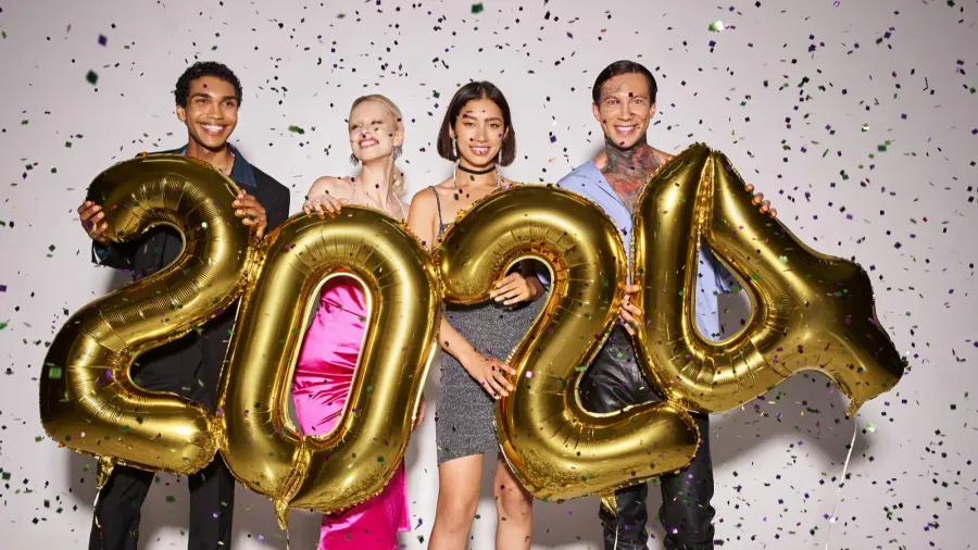 joyful multiethnic friends holding balloons with 2024 numbers near falling