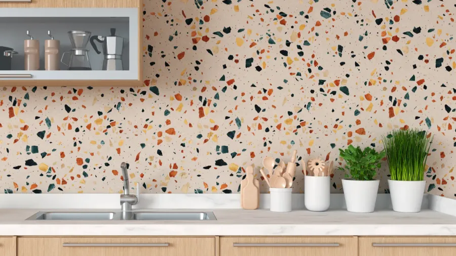 A modern kitchen with wooden cabinets, pants, utensils, sink, and a shelf on a terrazzo wall.