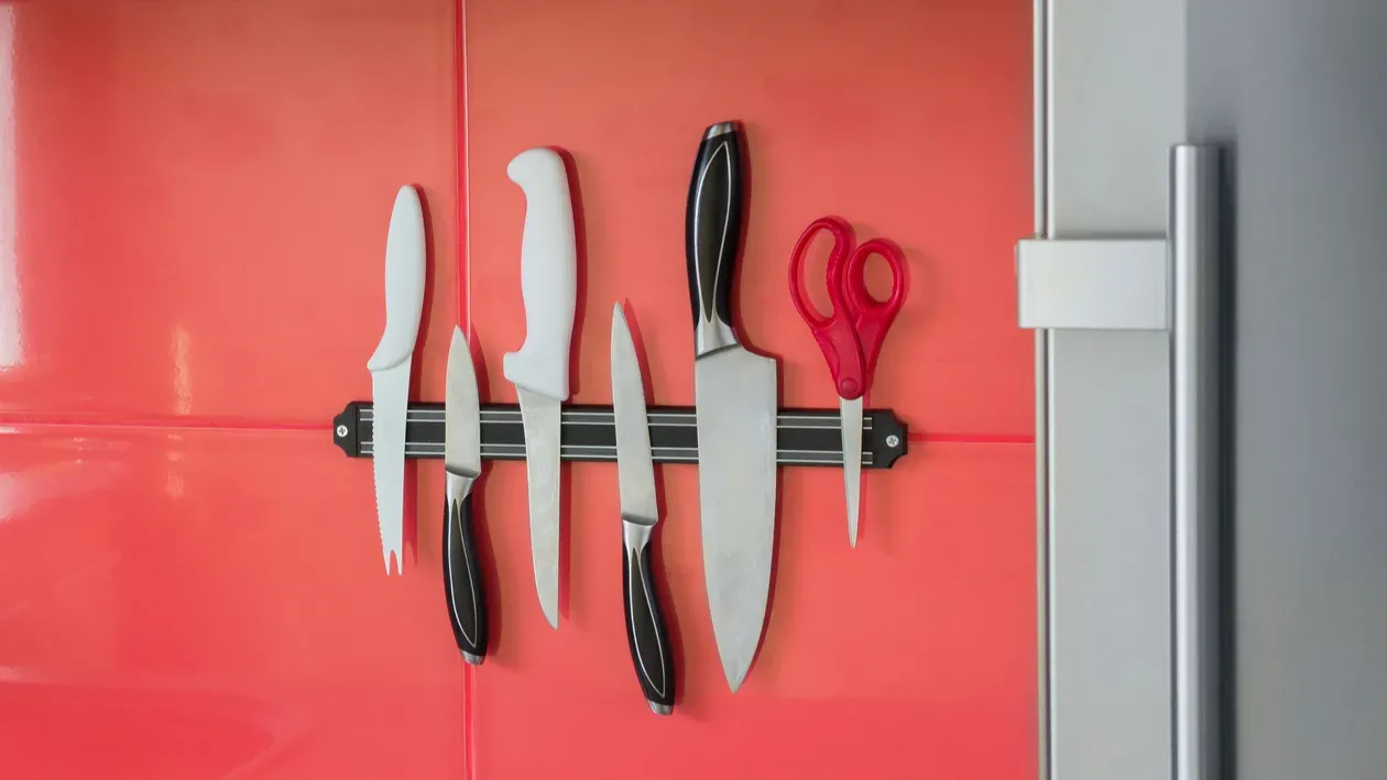 A magnetic knife strip holding knives and scissors.