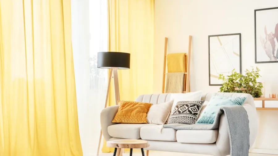 Cozy living room with a white sofa, colorful pillows, and yellow curtains.