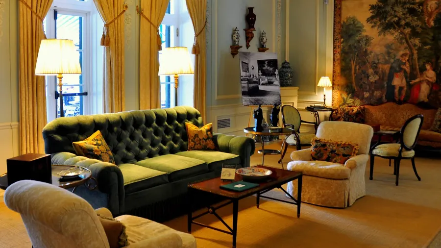 A luxurious sitting area filled with vintage furniture, including a green velvet sofa and patterned armchairs.