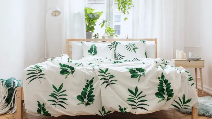 A serene bedroom with leafy bedding and plants, creating a fresh atmosphere.
