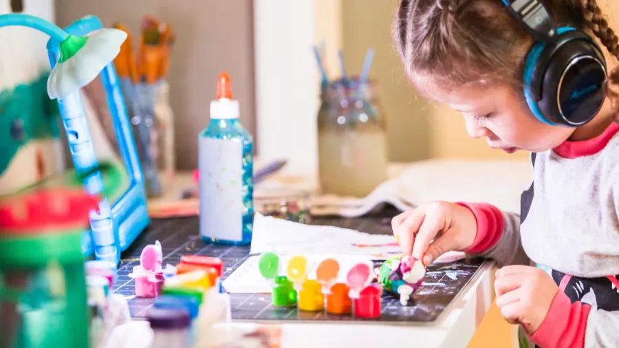 little girl wearing headphones listening to music and working on