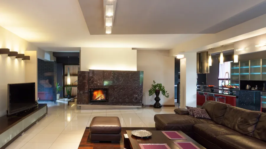 A spacious living room interior with cozy lighting, leather sofa, coffee table, and TV on a wooden console.