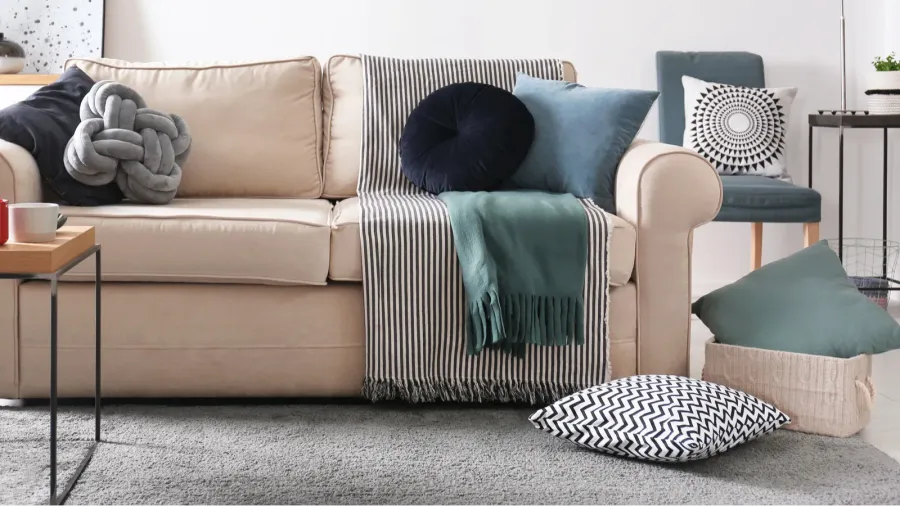A beige sofa with throw blanket and decorative throw pillows.