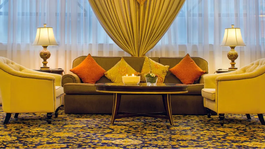 A living room interior with sofas, coffee table, and layered curtains.