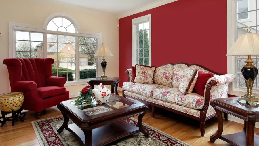 A living room interior with floral sofa, wooden coffee table, red armchair, side tables with lamps, and rug.
