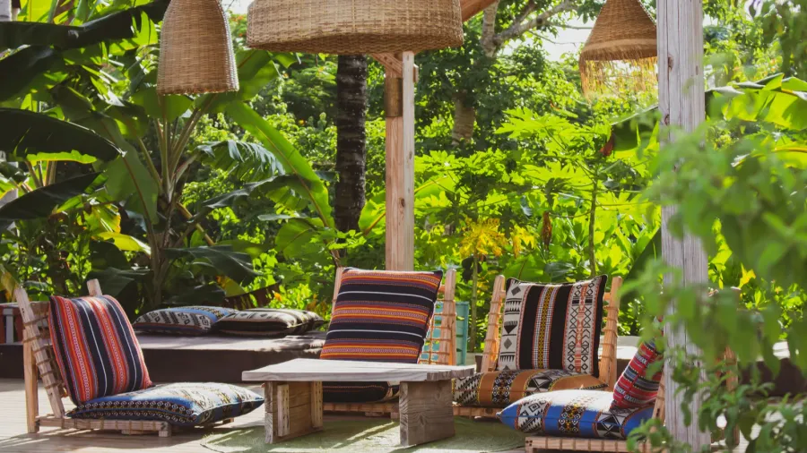 lounge chairs with pillows and table under straw lamps in
