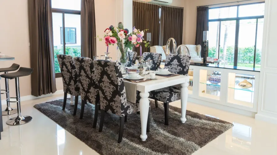 A luxurious dining room with white table and upholstered chairs on a cozy rug.