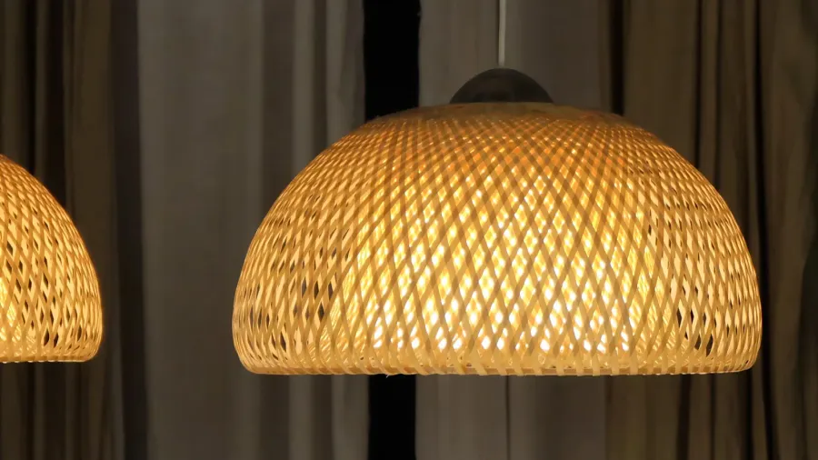 A close-up of a stylish woven pendant lamp that casts a warm glow.