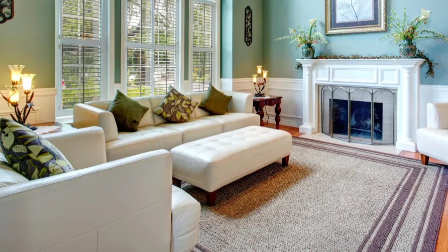 A cozy, well-decorated living room with white furniture and fireplace.