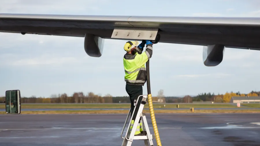 male worker refueling airplane while standing on step ladder