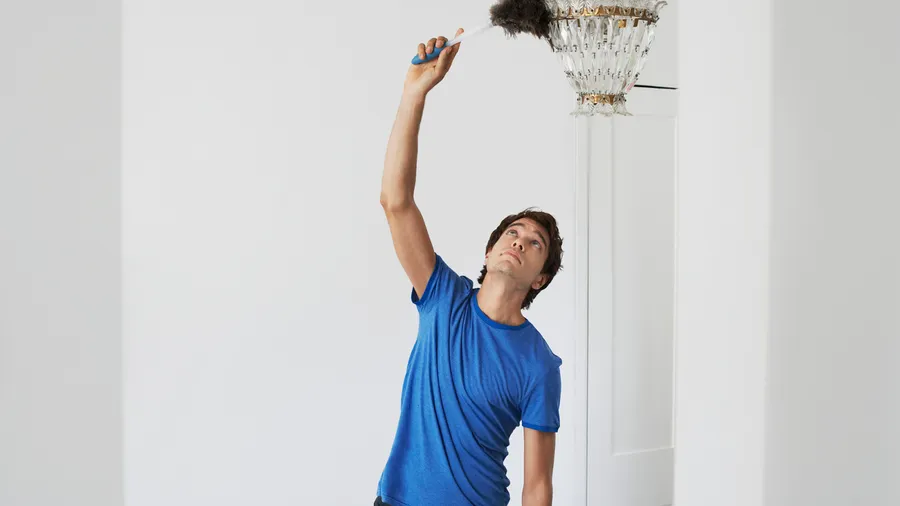 Man dusting crystal chandelier