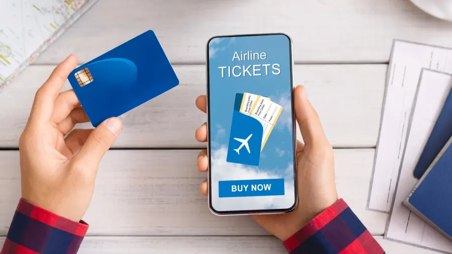 man holding credit card and smartphone buying plane tickets online
