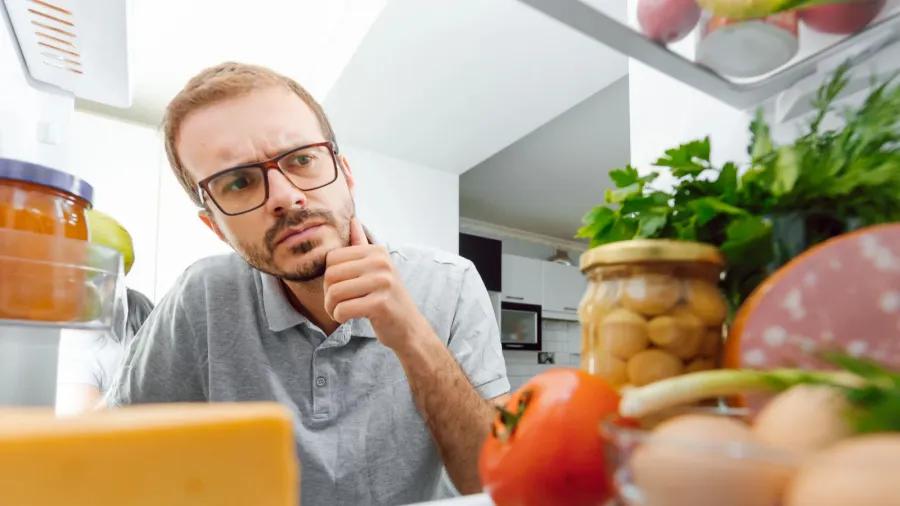 man looking inside fridge full of food