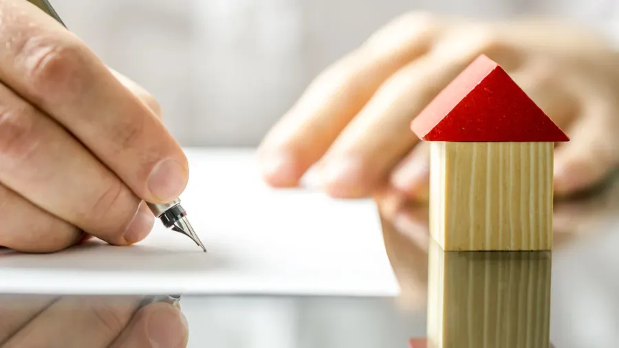 man signing a contract when buying a new house