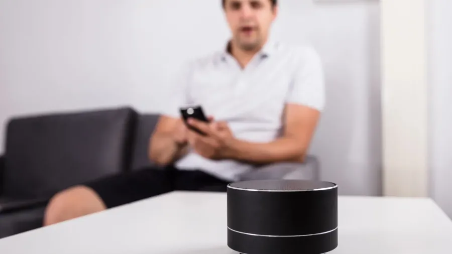 man with laptop listening to music on wireless speaker at