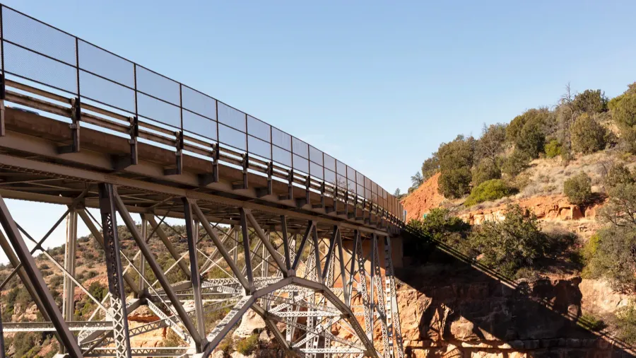 metal construction of bridge supports against blue sky and rocks