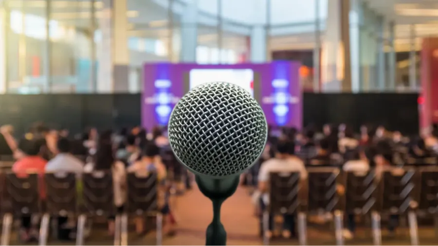 microphone over the abstract blurred photo of conference hall or