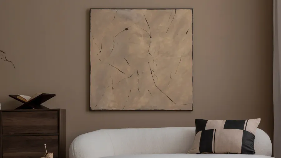 A beige living room interior with curved sofa and abstract wall art.