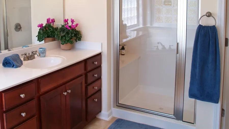 A bathroom interior with wooden vanity with brushed nickel hardware.