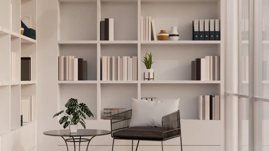 A minimalist reading nook displays neatly organized shelves, a black chair, and a small table.