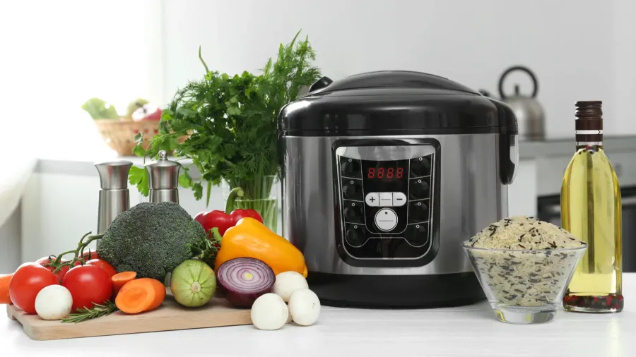 modern multi cooker and products on table in kitchen space