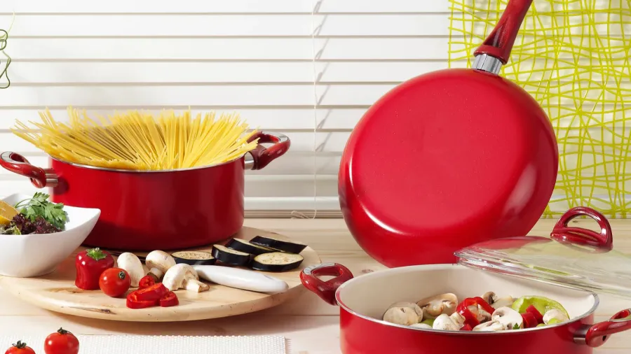 Kitchenware featuring red pots, spaghetti, and vegetables.