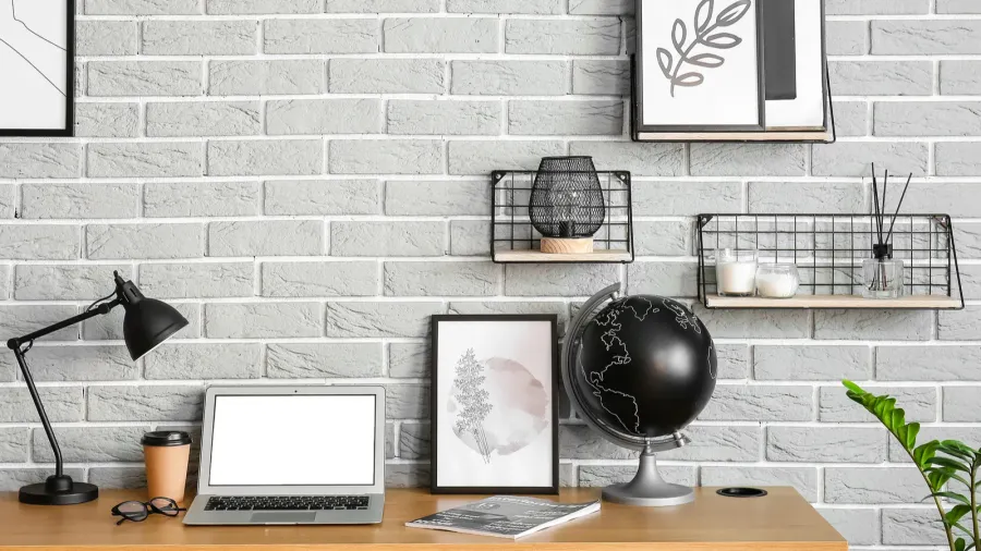 modern workplace with laptop and frames near brick wall