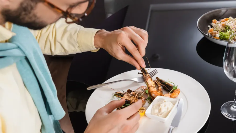 muslim man sitting near tasty shrimps and water on table