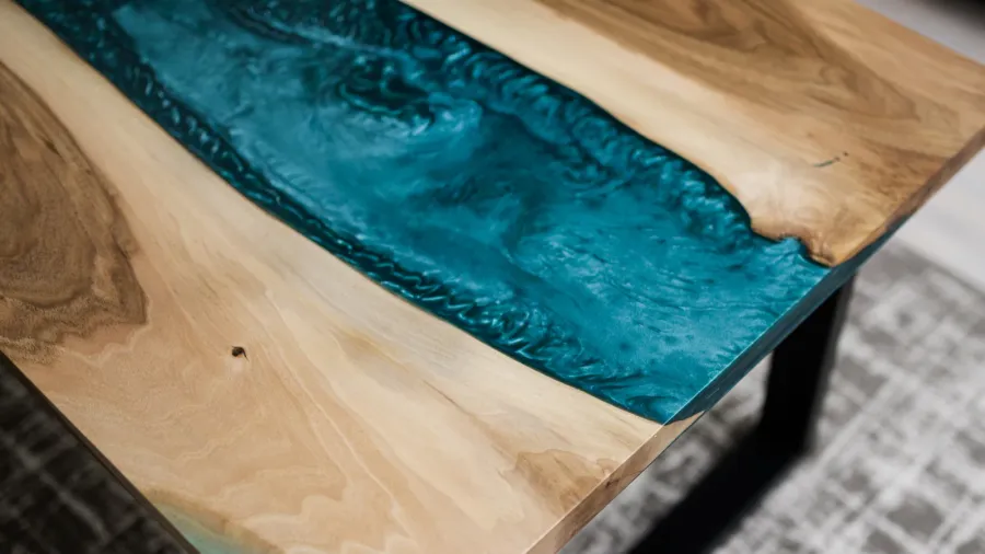 A close-up of a wooden table featuring an artistic inlay of turquoise resin.