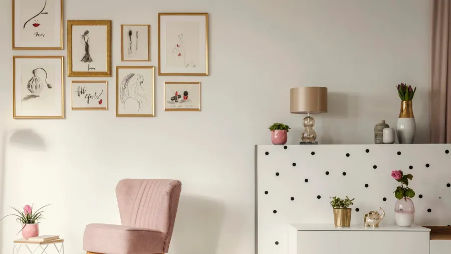 Cozy corner with a pink upholstered armchair, small pink plant pot, and wall art.