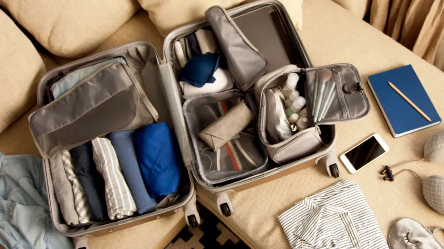 open grey suitcase with different clothes packed for journey at