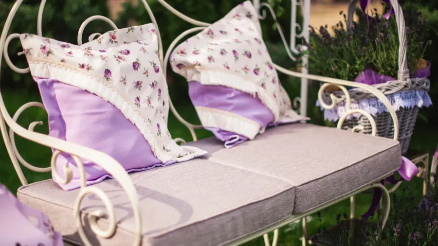 A metal bench with soft cushions and throw pillows on it.