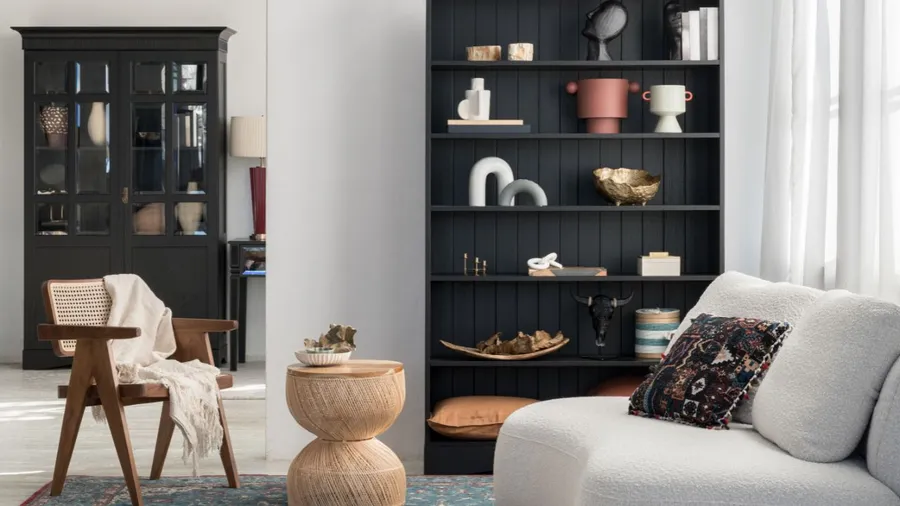 Contemporary living room with dark furniture, black shelving, and white curtains.