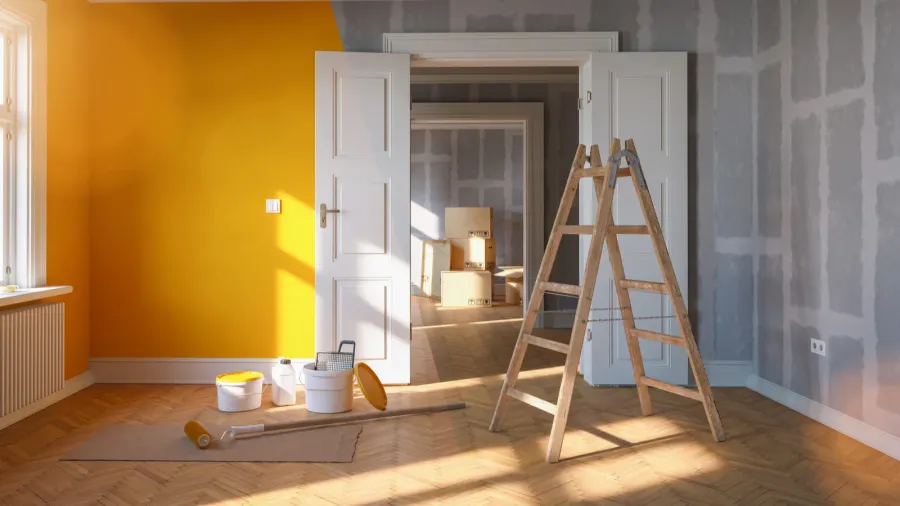 Room with yellow wall, painting supplies, and an open doorway.