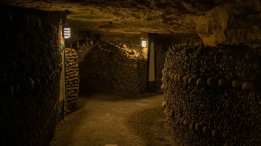 pathway in catacombs old skulls and bones form walls grim