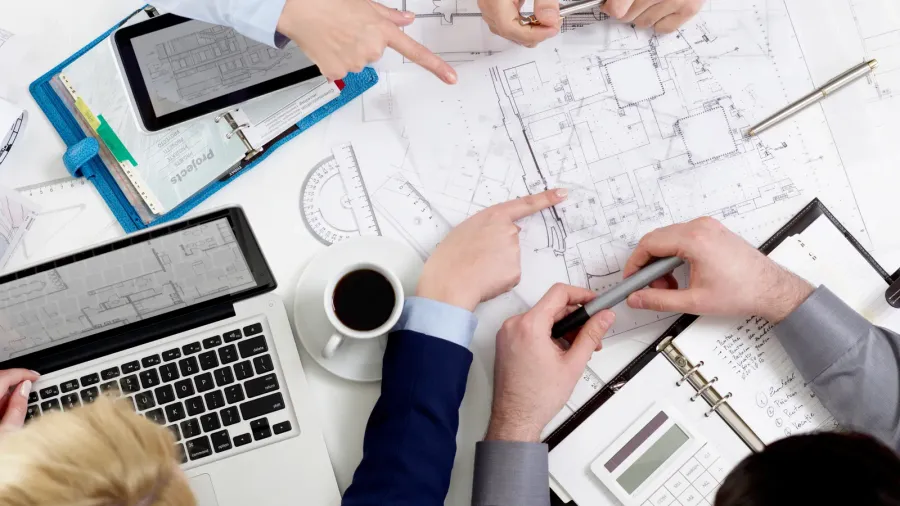 people reviewing blueprints at desk