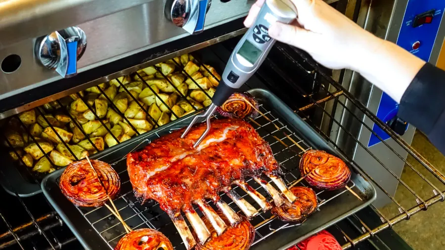 person checking temperature of rack of lamb
