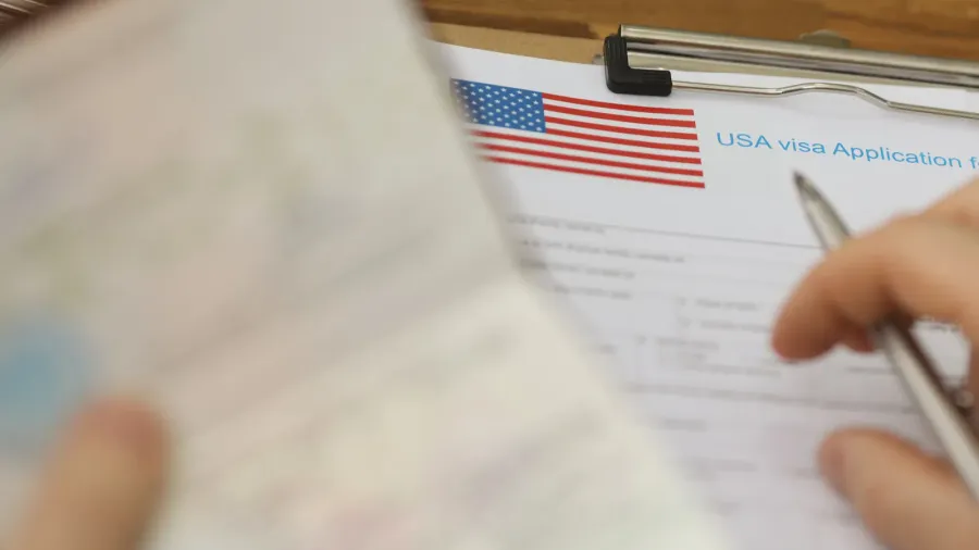 person filling visa application forms holding personal passport