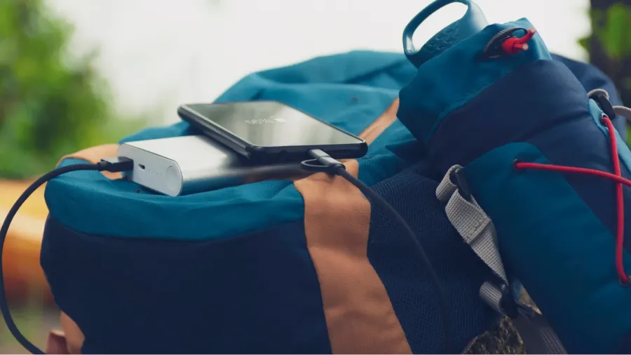 portable travel charger power bank charges smartphone against a backdrop