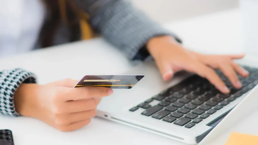 Beautiful young Asian woman using a credit card with her laptop.
