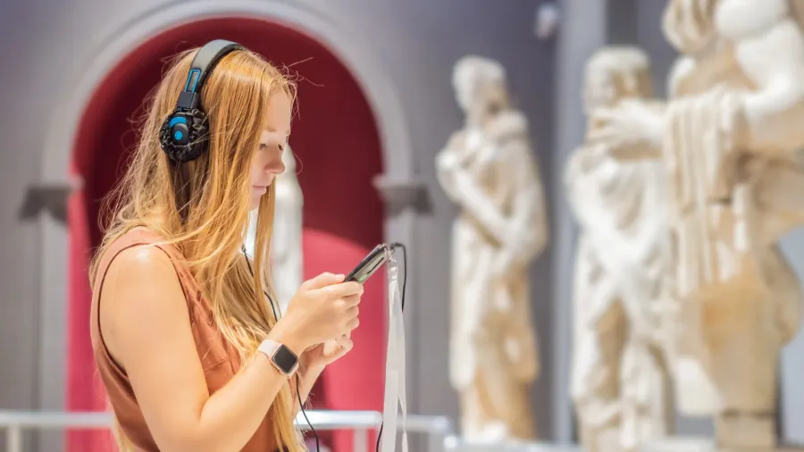 portrait of contemporary young woman looking at sculptures and listening