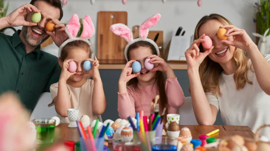 portrait of playful caucasian family covering eyes with easter eggs