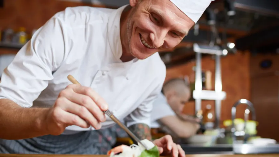 portrait of professional chef plating asian seafood dish in restaurant